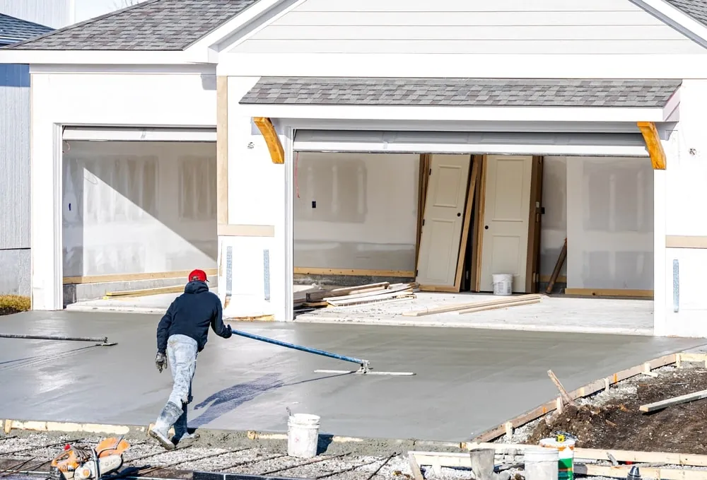 Contractor smoothing out a concrete driveway